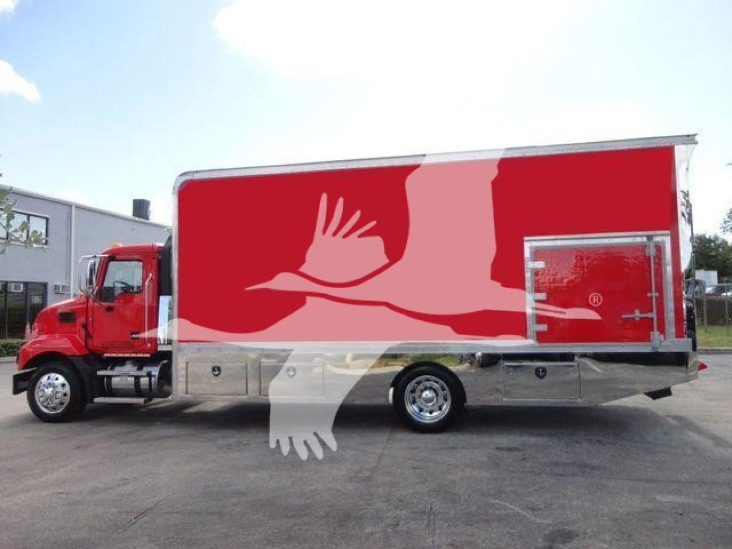 Md6 rollback truck side view showing red cab and large red box with white crane or bird artwork on side door area.
