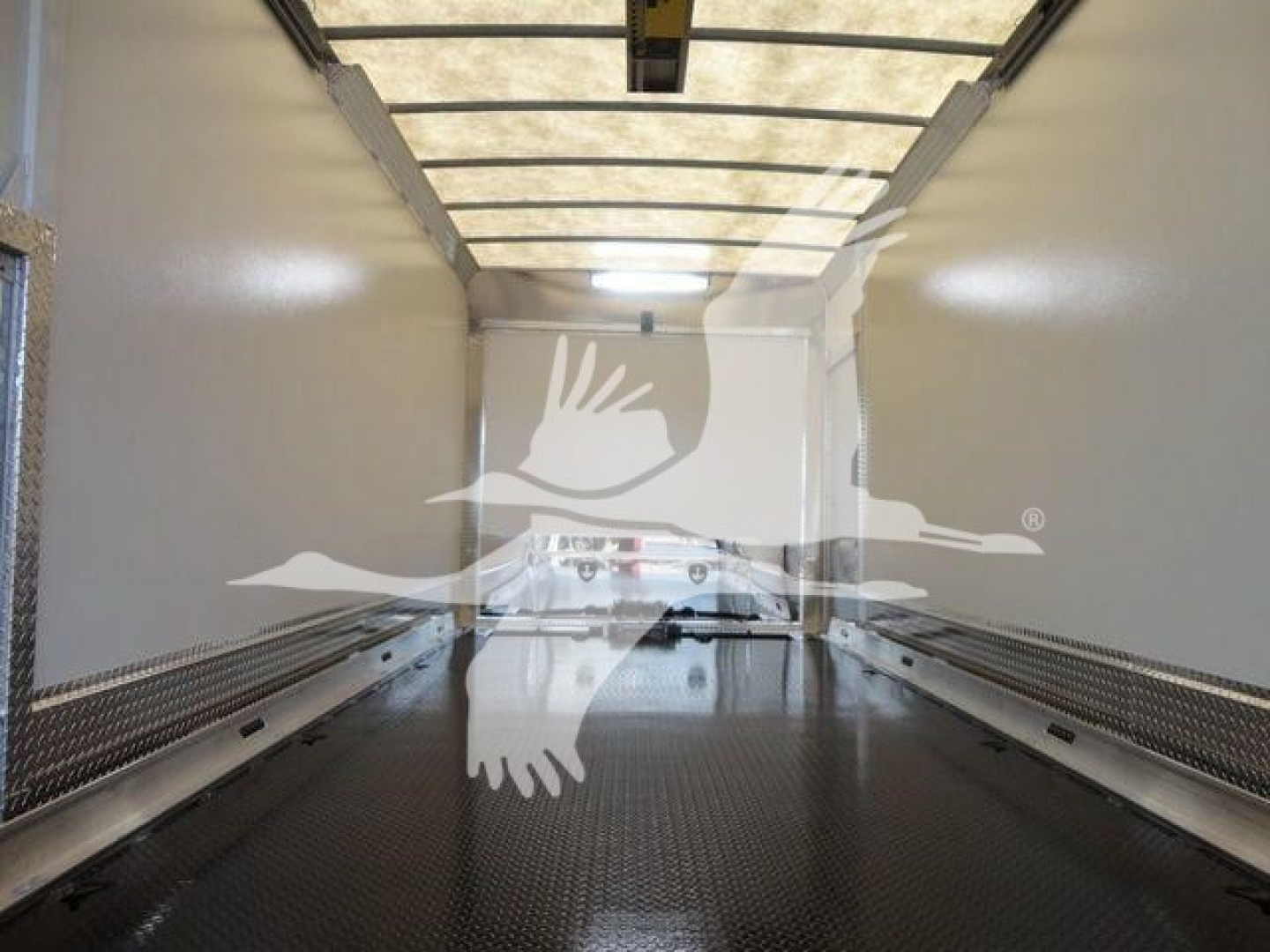 Truck bed interior of a Mack MD6 rollback truck showing blank walls and diamond-plate flooring.