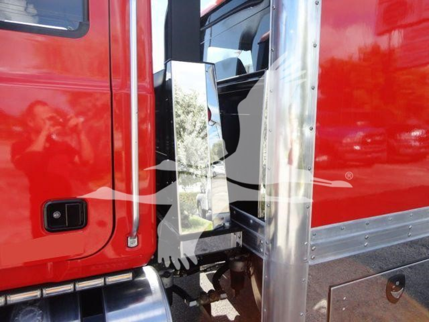 Truck cab area showing door and chrome mirror attachment with a red cab and silver trim.