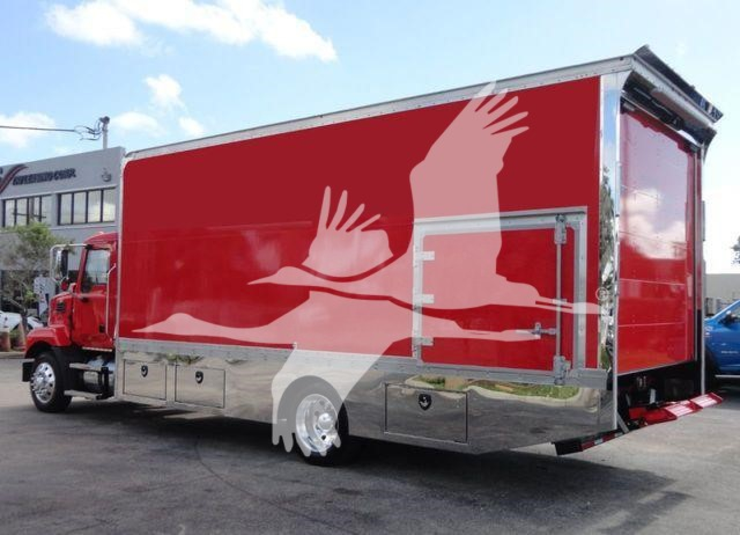 MD6 rollback truck body with red wrap and silver lower panels, side storage compartments, rear access door, and graphic silhouette art.