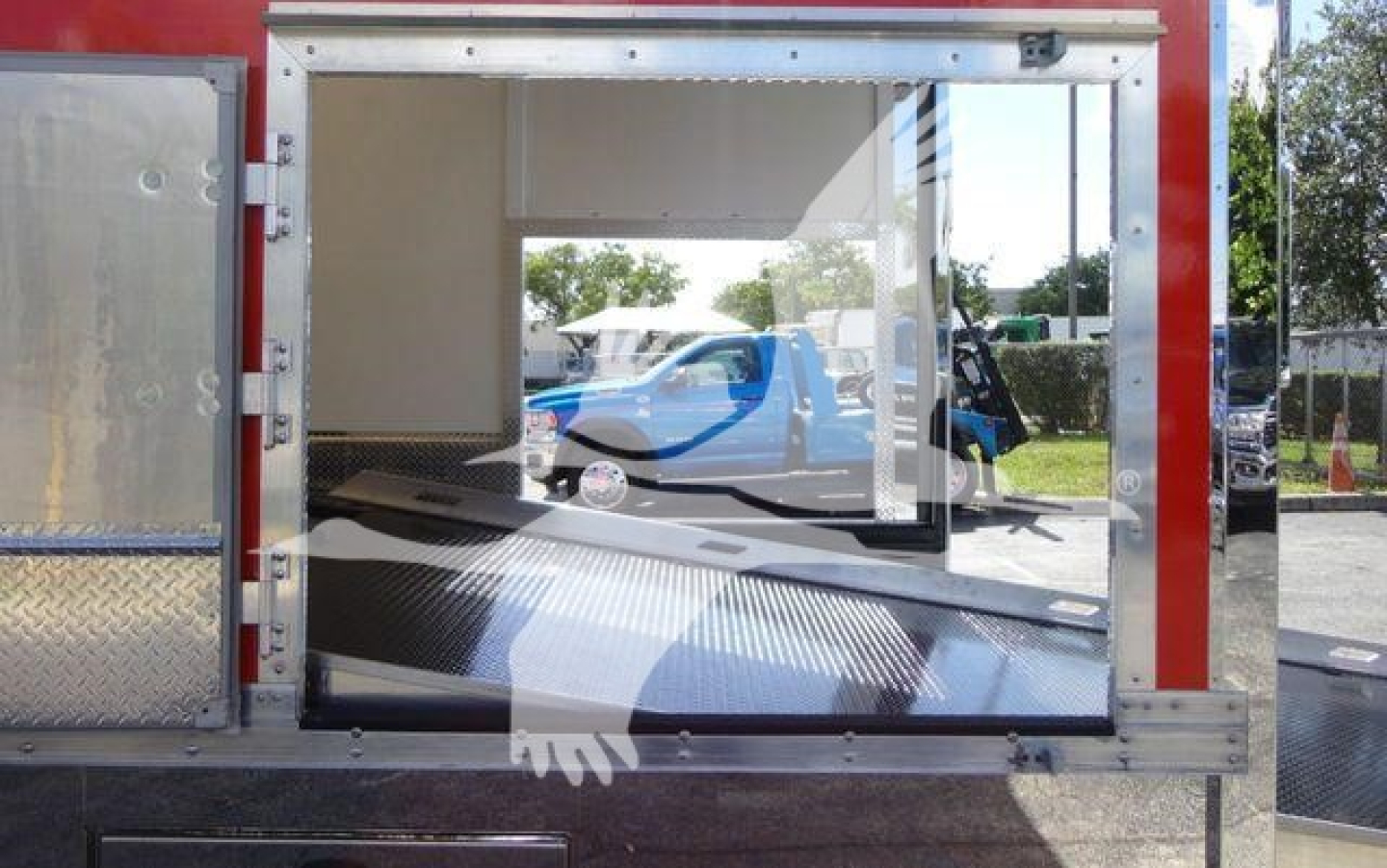MD6 rollback truck body with open rear cargo space and reflective surfaces showing interior ramp and hydraulic equipment.