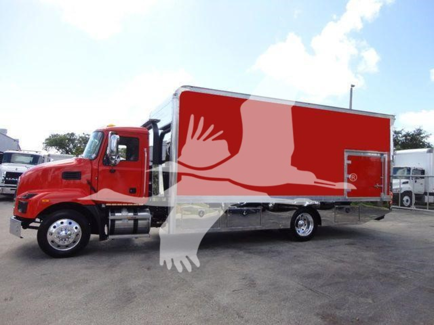 MD6 rollback truck showing red cab and large red cargo box with white logo; side view of Mack MD6 box truck in a dealership lot.