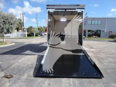 MD6 empty rollback truck with a lowered black steel ramp at the rear, interior cargo area visible, light gray walls, and a bright exterior scene.