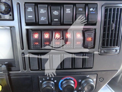 Dashboard view of a 2027 Mack MD6 rollback truck showing control switches, indicator gauges, and climate controls with labeled buttons.