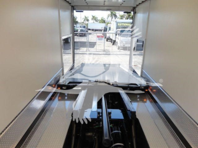 Aluminum flatbed of a new Mack MD6 rollback truck showing the interior from rear, with diamond plate surfaces and hydraulic components visible near the center.