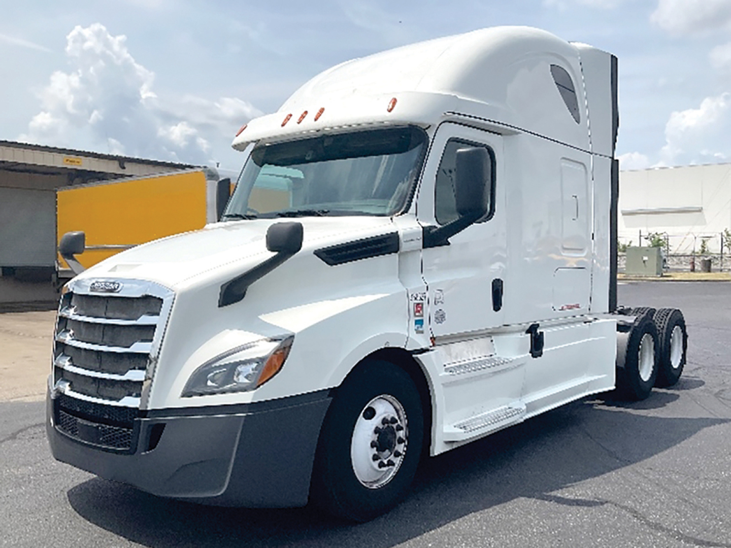 Truck cab side view showing Freightliner Cascadia126 with white exterior, sleeper cab, triple rear axles, large grille, and side mirrors.