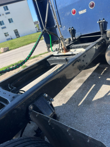 Truck chassis frame and fifth wheel area of a 2005 Peterbilt 379 EXT tractor showing frame rails, cab mounting, air lines, and rear area near the sleeper. Visible badges and blue paint.