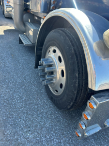 Peterbilt 379 EXT front wheel area showing aluminum fender, large dual rear tires, chrome hub with multiple lug nuts, and chrome chrome fuel tank and steps.