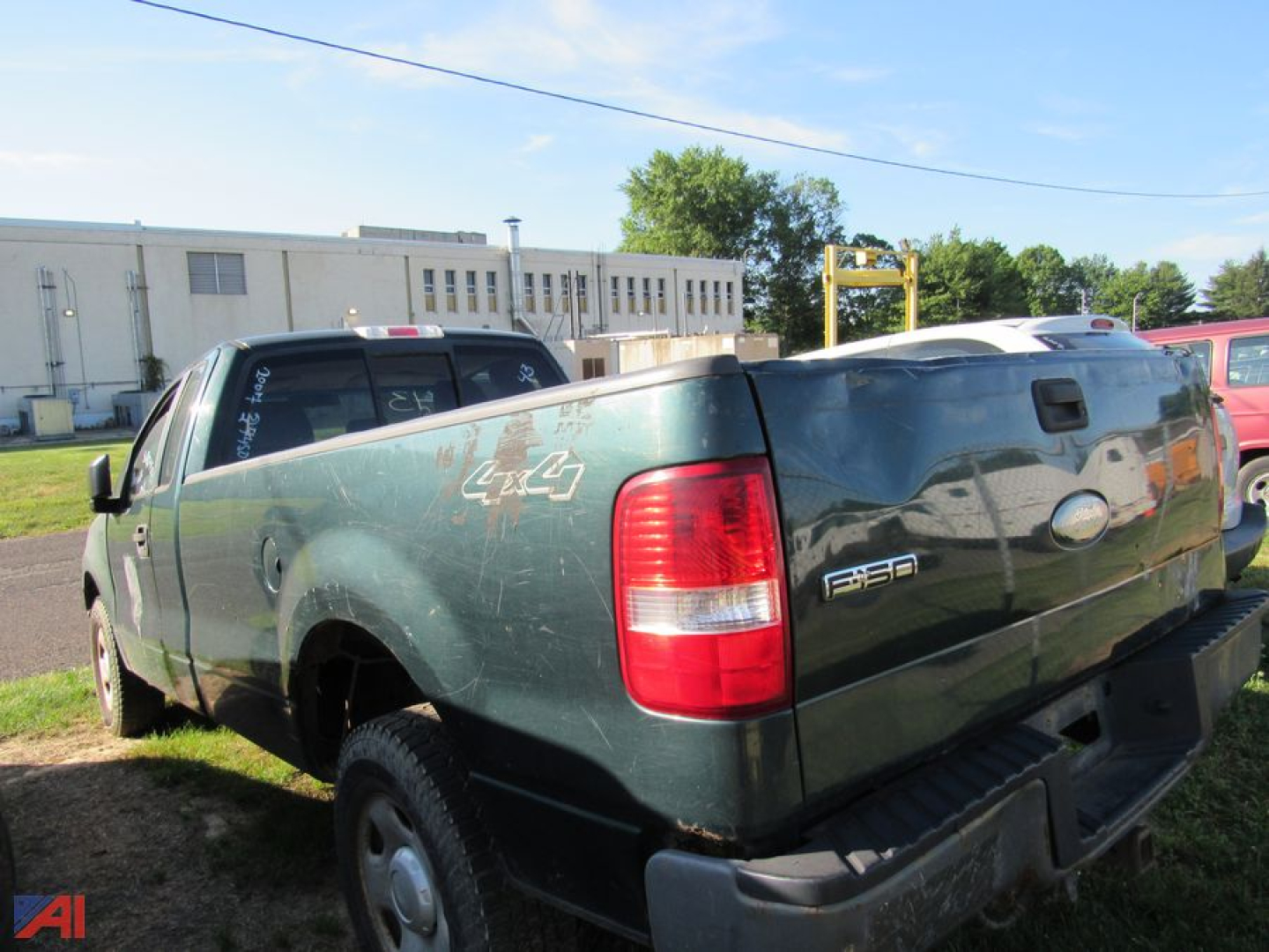 2007 Ford F-150 pickup truck rear quarter and tailgate showing F-150 badge and scratched green body in a used lot.