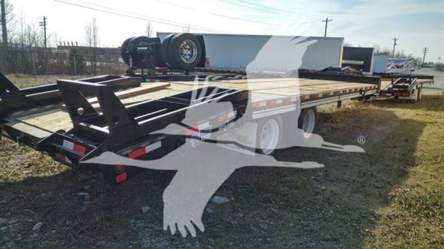 Flatbed trailer in-service showing dual axles and gooseneck hitch with spare tire and blue brand logos on the deck.