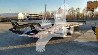 Flatbed trailer showing long steel deck with dual axle, rear loading ramps, and reflective safety tape.