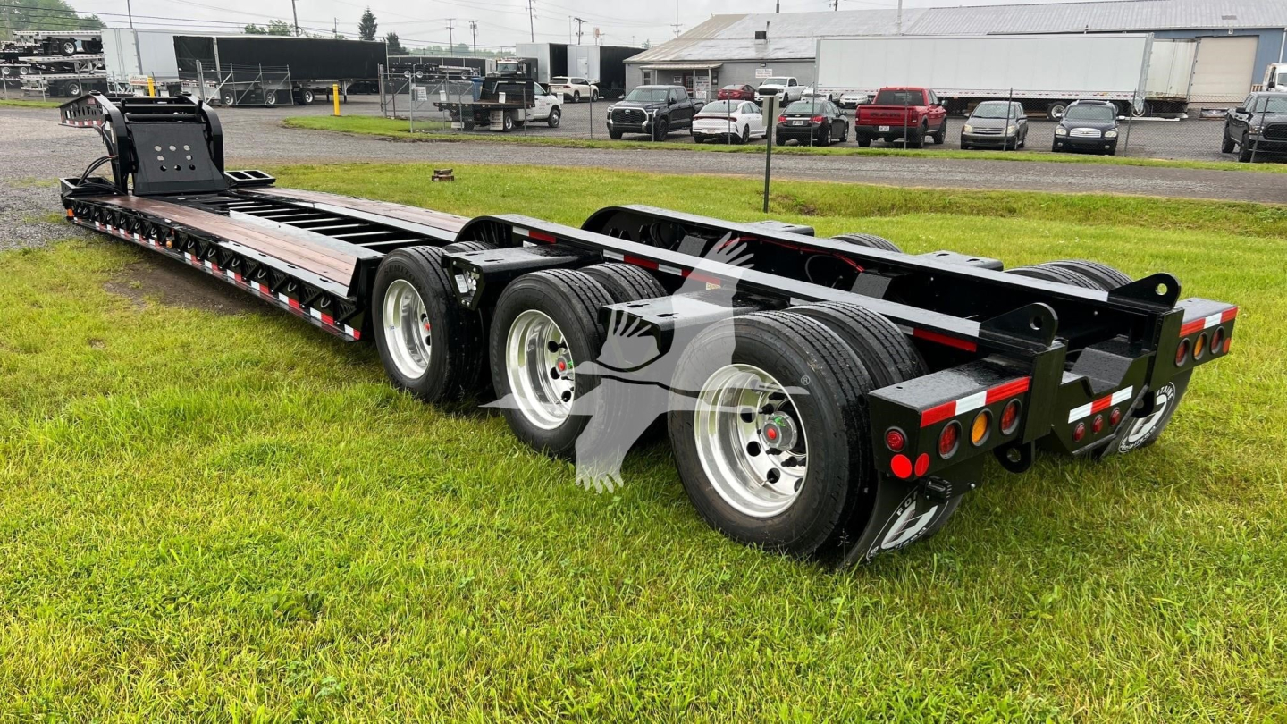 Fontaine 55 Lcc lowboy trailer showing dual rear axles and long flatbed with black frame and red accents.