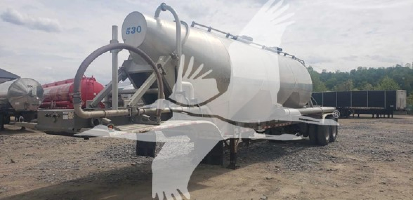 Pneumatic dry bulk trailer tank in side view showing cylindrical stainless steel tank with rounded ends and support legs under trailer.