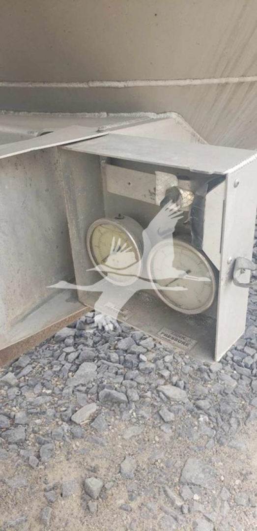 Trailer wheel hub assembly and brake drum visible in an access opening of a pneumatic dry bulk tank trailer.