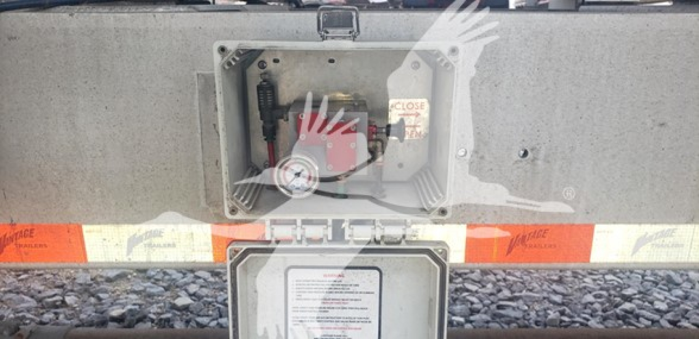Trailer rear hatch showing manway access area, warning label, and interior lift mechanism of a sand tank trailer (Vantage Sand Tank) with safety decals.