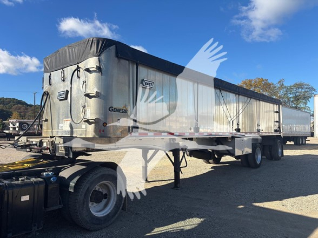 Dump trailer in the yard showing East Geness branded aluminum bed with tarp cover, undercarriage, and wheels visible.
