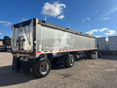 Dump trailer in service showing side panels with faded graphic and rear door