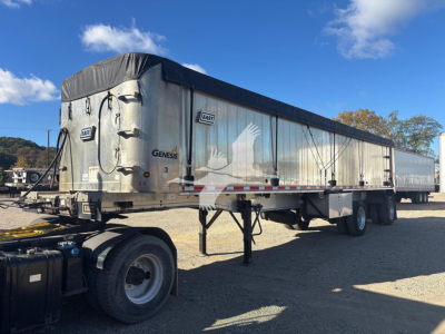 Semi trailer showing Genesis East dump trailer with silver sides and black tarp cover, parked in lot. Visible labels: GNS? and East brand logos along side.