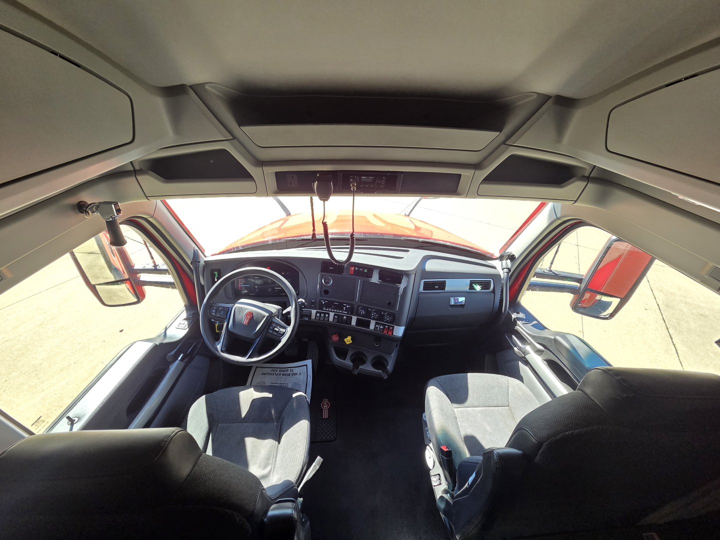 Truck cab interior showing steering wheel, dashboard, and driver seat in Kenworth T680 with visible gauges and controls.
