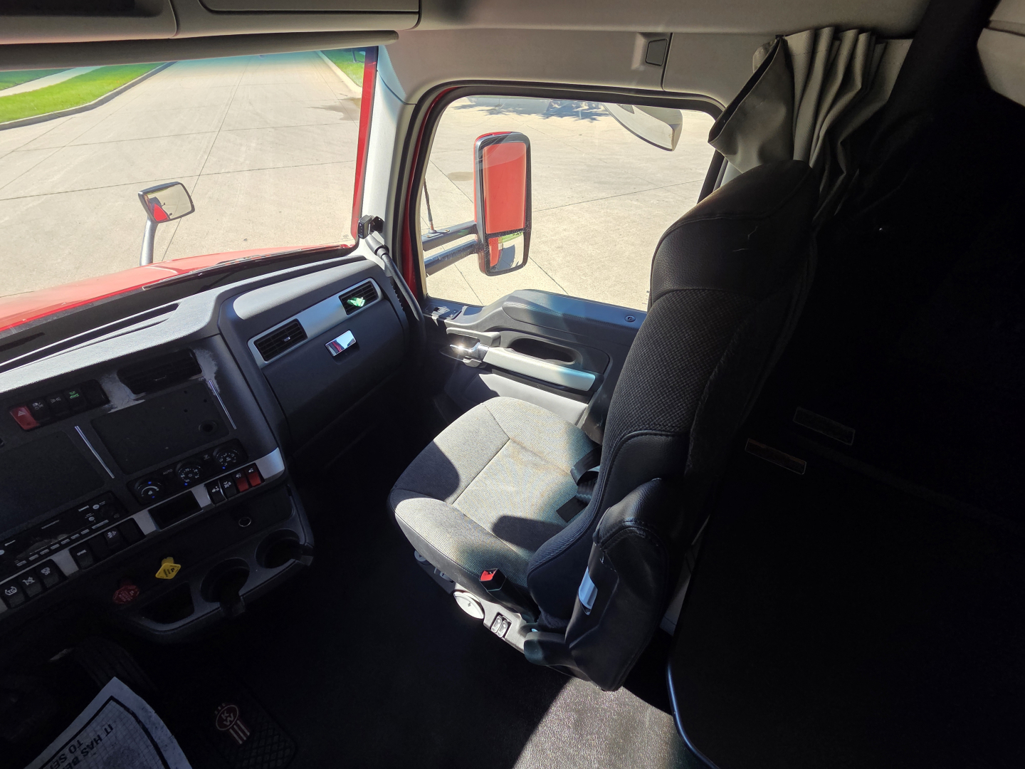 Kenworth T680 cab interior showing driver seat and dashboard with steering wheel and side window