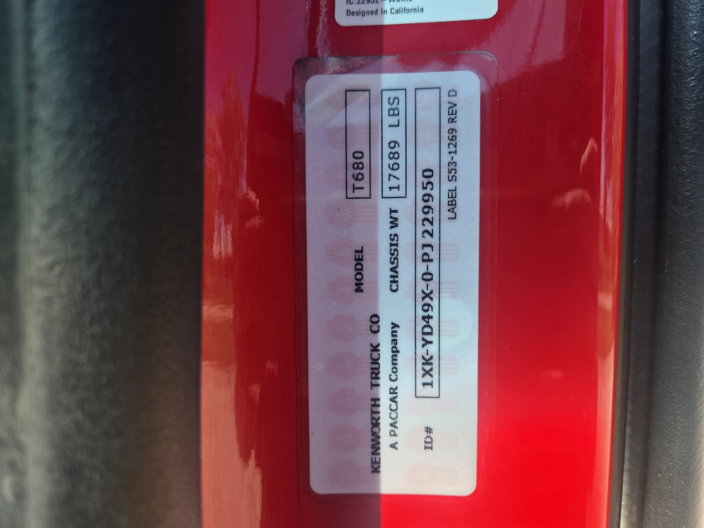 Kenworth T680 VIN sticker and label on red truck door showing model and serial numbers.