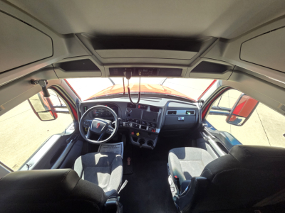 Truck cab interior showing steering wheel, dashboard, and driver seat in Kenworth T680 with visible gauges and controls.