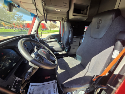Kenworth T680 cab interior showing steering wheel and driver seat, dashboard, and passenger seat in view.