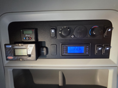 Kenworth T680 dash cluster showing control knobs, digital display, and a GTU device with blue backlit screen.