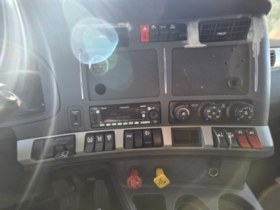 Kenworth T680 dash cluster showing switches, knobs, and instrument panels with red and yellow controls.