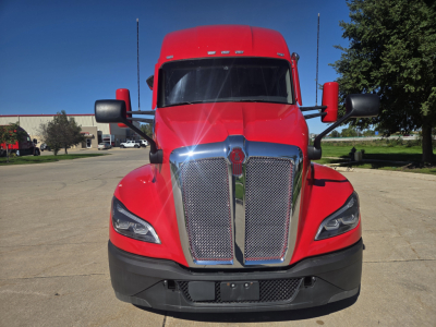 2023 Kenworth T680 front view showing bold grille, red cab, large chrome grille surround, black bumper, KW emblem, side mirrors