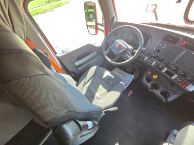 Kenworth T680 truck interior cockpit showing steering wheel, dashboard, and driver seat with gray fabric.