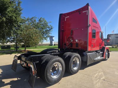 Kenworth T680 sleeper tractor chassis with red cab, rear view showing dual rear axles and chrome wheels.