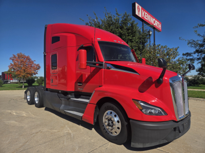 Kenworth T680 conventional sleeper truck in red, left front three-quarter view with black bumper and chrome grille; Kenworth sign in background.