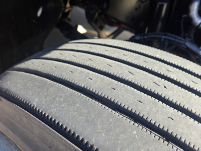 Kenworth T680 wheel/tire close-up undercarriage showing tread and suspension components.