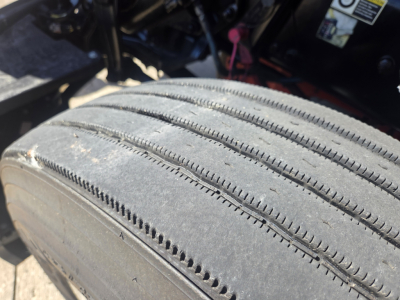 Kenworth T680 wheel/tire close-up with tread details and part of chassis visible.