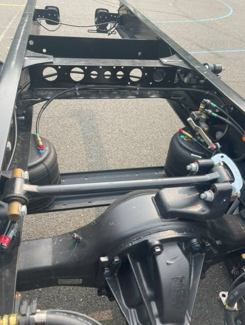 Front frame of a cab chassis truck showing rear suspension air springs and chassis rails with wiring and fittings.