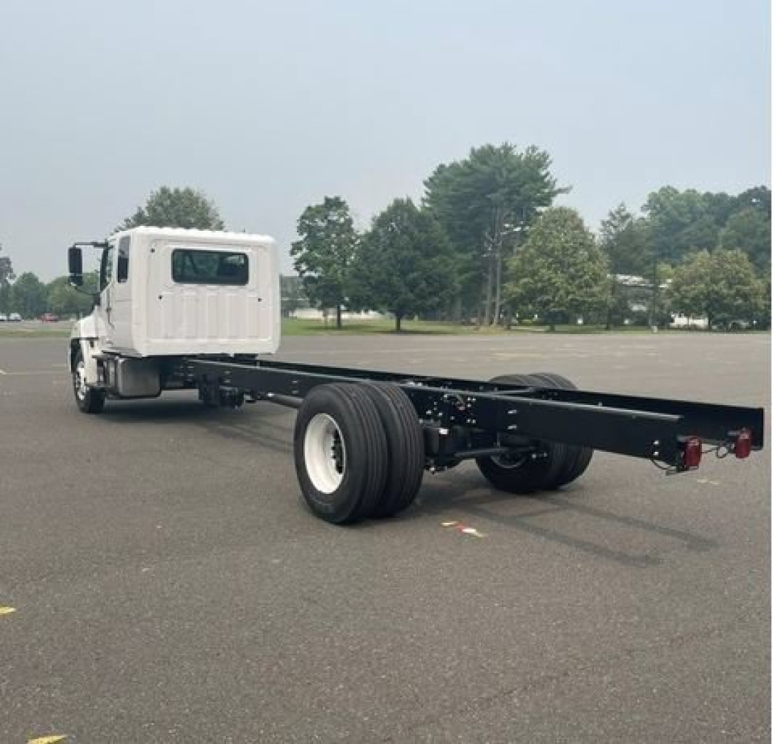 Truck cab chassis showing long wheelbase frame and dual rear axles with white cab and black frame.