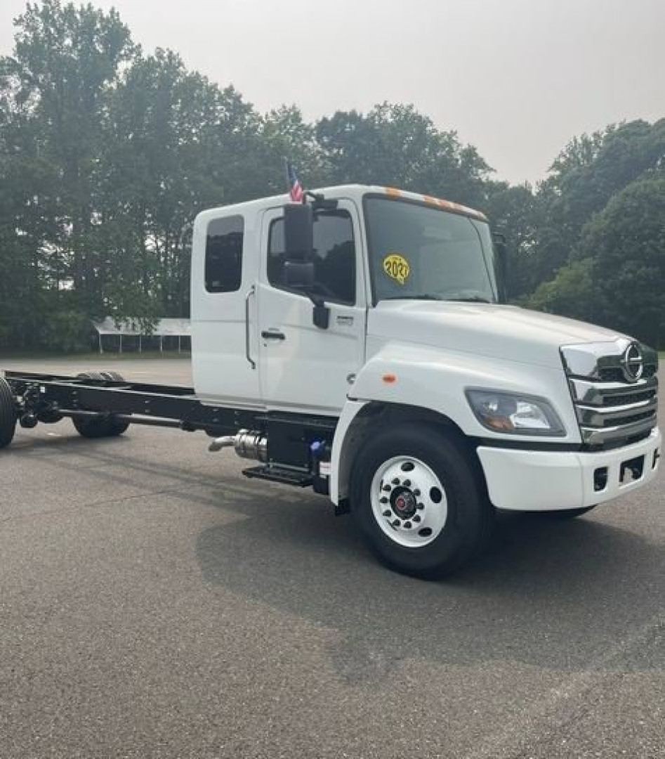 Cab chassis truck showing white Hino L6 with extended chassis and dual rear wheels, front grille and headlights visible.