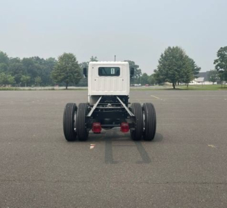 Rear view of a white cab-chassis truck on a parking lot showing dual rear axles and chassis framing.