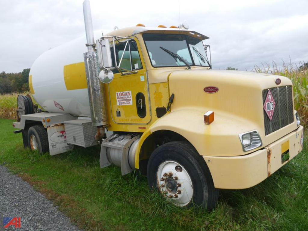 Peterbilt 330 day cab with a large cylindrical LPG tank mounted behind the cab, yellow paint, side mirror, front grille, and warning placards visible.