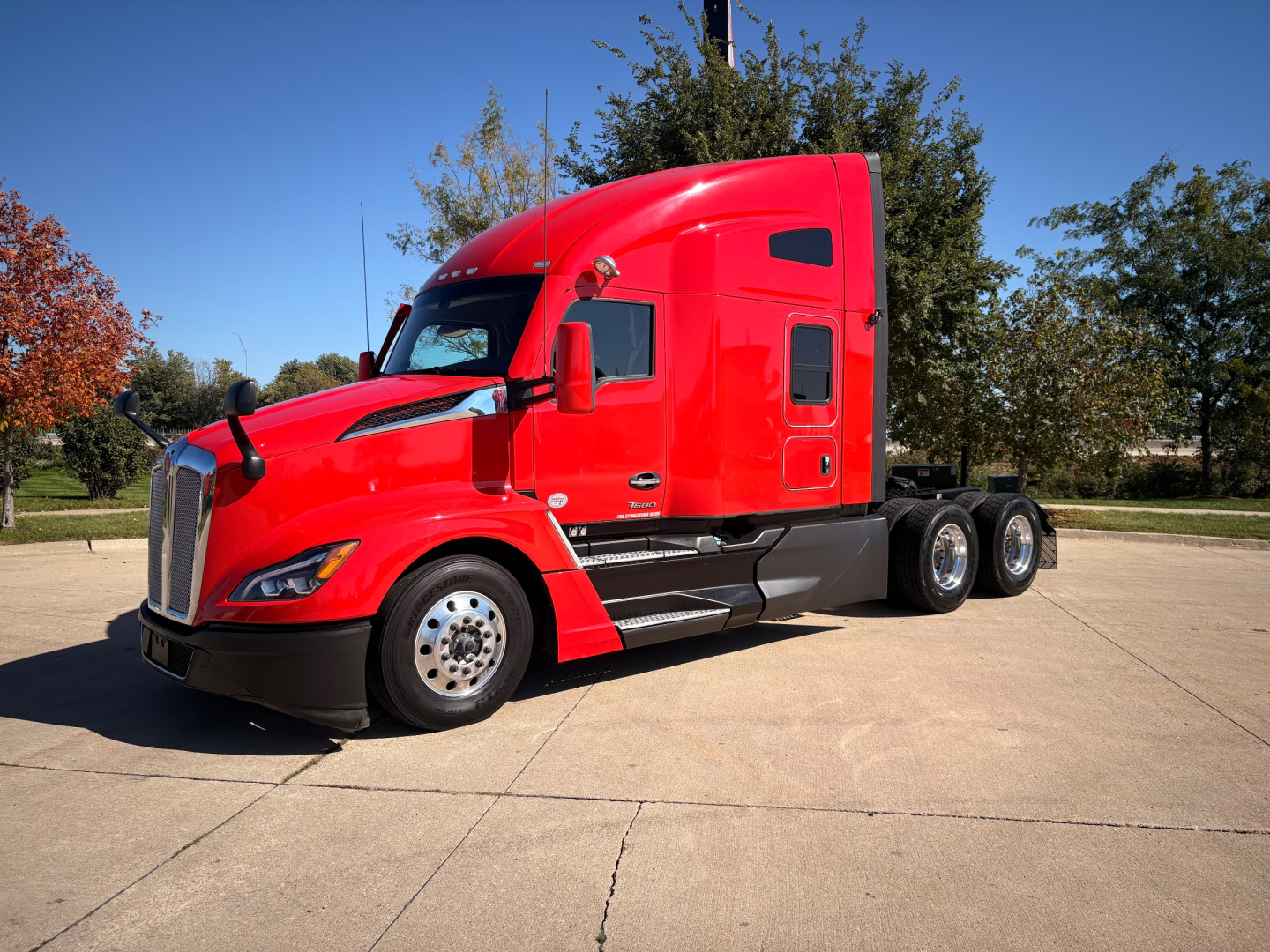 Kenworth T680 sleeper cab in red, side view showing front and rear wheels and cab details.