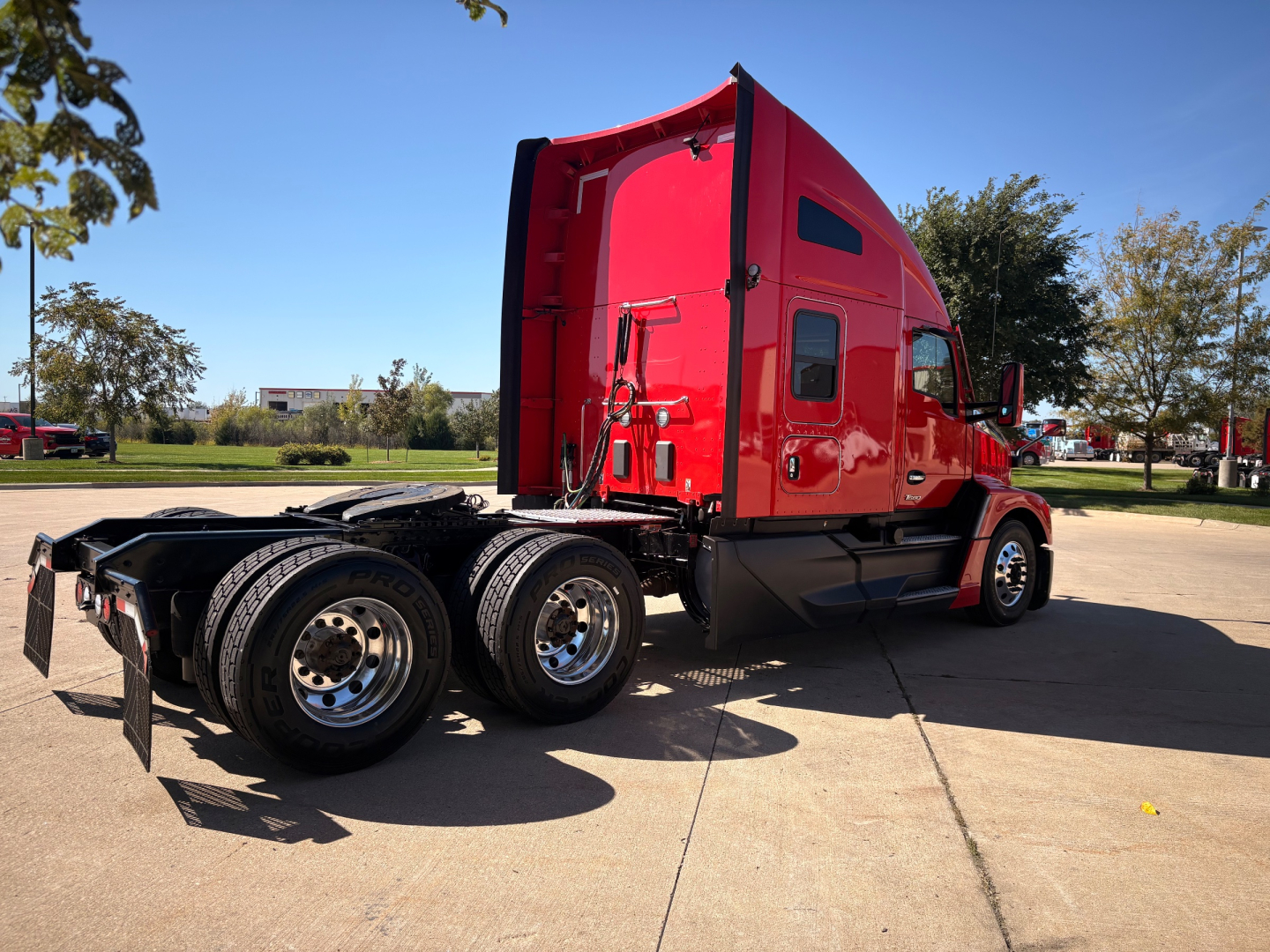 Kenworth T680 sleeper cab semi-truck side/rear view showing red cab, black chassis, six wheels, and absent trailer.