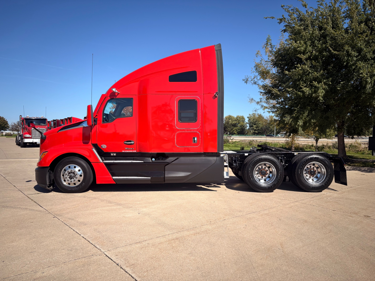 Kenworth T680 tractor in red with sleeper cab, side profile showing 6-wheel rear, wheels and chassis visible.