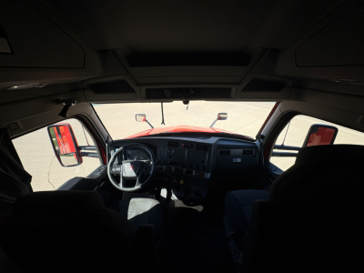 Kenworth T680 truck cabin interior view from driver seat showing steering wheel, dashboard, and windshield with side mirrors.
