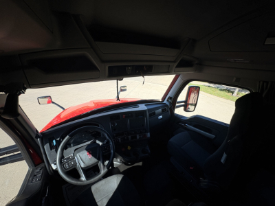 Kenworth T680 truck interior showing steering wheel, dashboard, and driver seat area from passenger side window view.