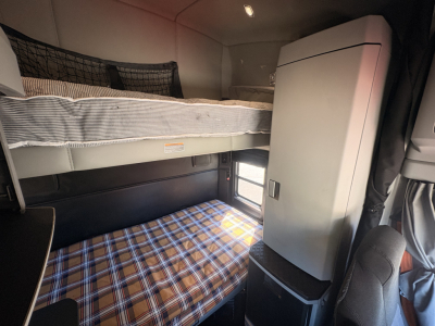 Kenworth T680 sleeper cab interior showing bunk bed and storage cabinet.