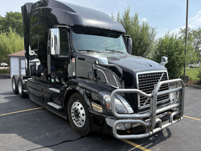 Volvo VNL 780 tractor in black with chrome grille and bumper guard. Front view shows large bull bar with tubular guard, chrome mirrors, and aerodynamic side skirts.