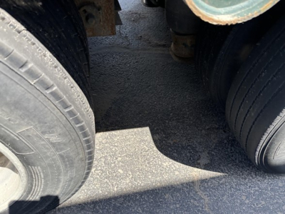 Trail King lowboy trailer wheel area showing dual rear axles and tires with visible tread and metal frame undercarriage.