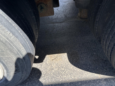 Trailer wheel well area showing dual rear tires of a lowboy trailer with some metal frame components.
