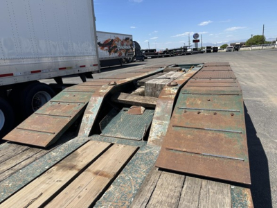 Lowboy trailer deck with kickout ramps and weathered steel sections visible.